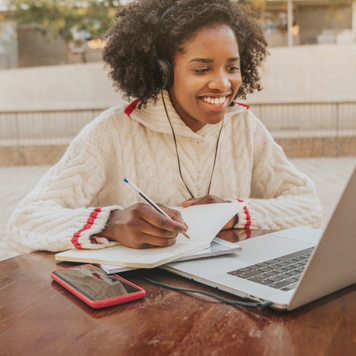 Young female student using a laptop and credit card outside on campus