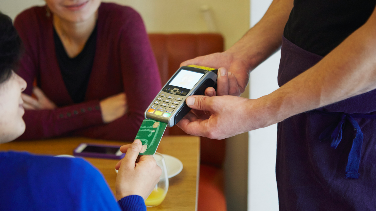 Cropped shot of woman inserting card into credit card machine in restaurant