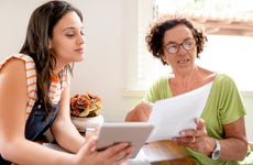 Woman helping her mom with home finances using a digital tablet