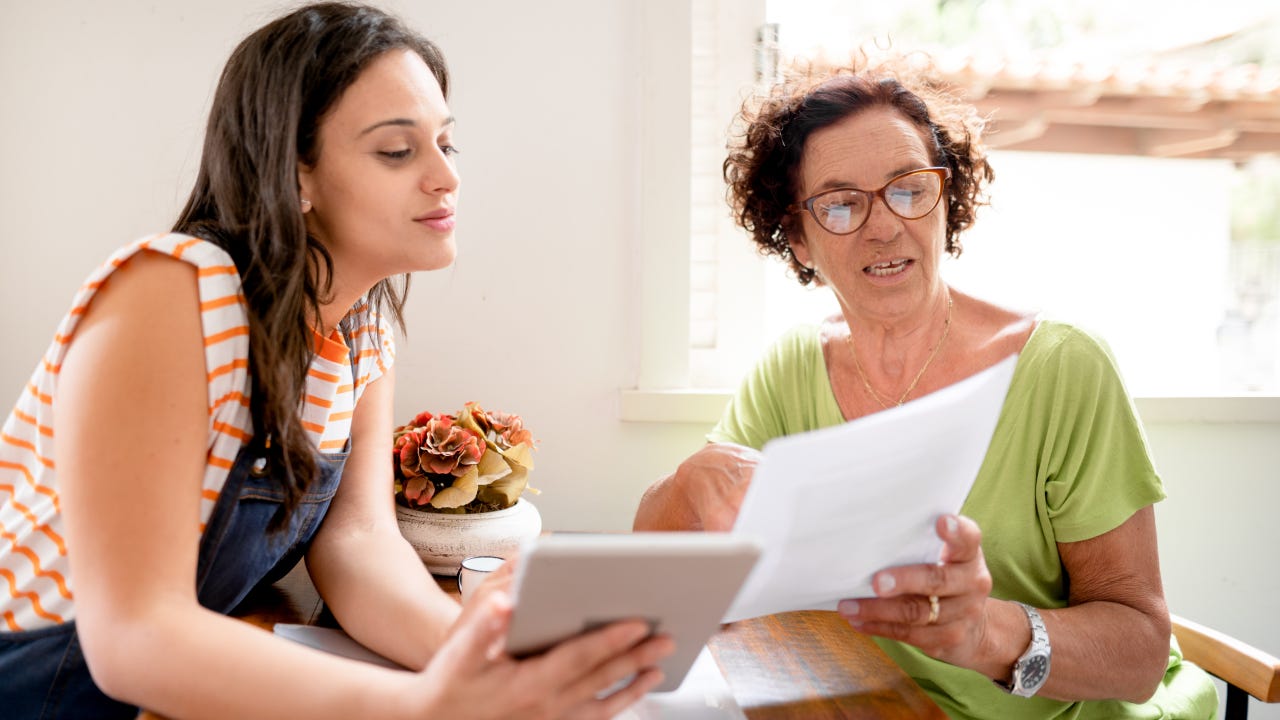 Woman helping her mom with home finances using a digital tablet