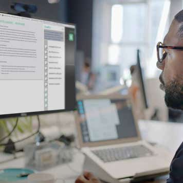 man’s face looking into a computer screen in an open plan working office