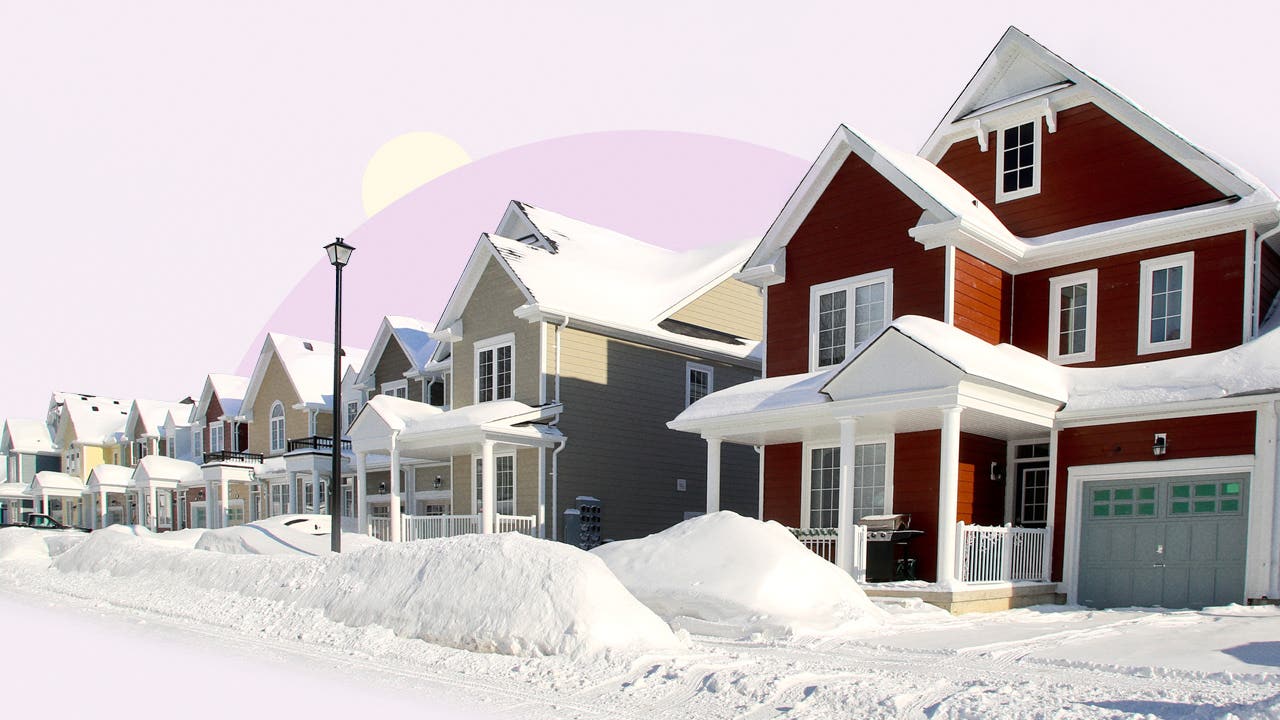 A row of houses with snow-covered sidewalks and streets
