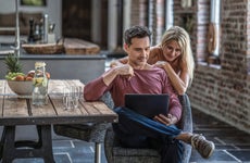 couple siting in country house kitchen, looking at laptop