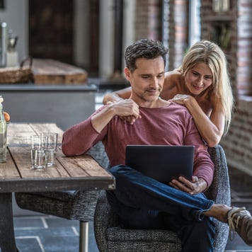 couple siting in country house kitchen, looking at laptop