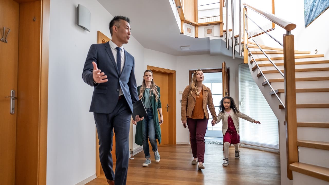 real estate agent showing house for sale to 2 women and child