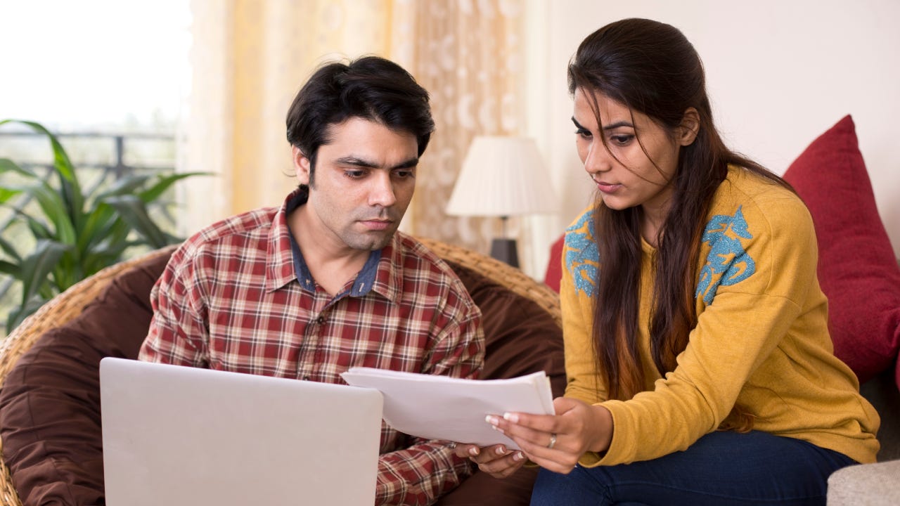 Young couple reading financial bill at home