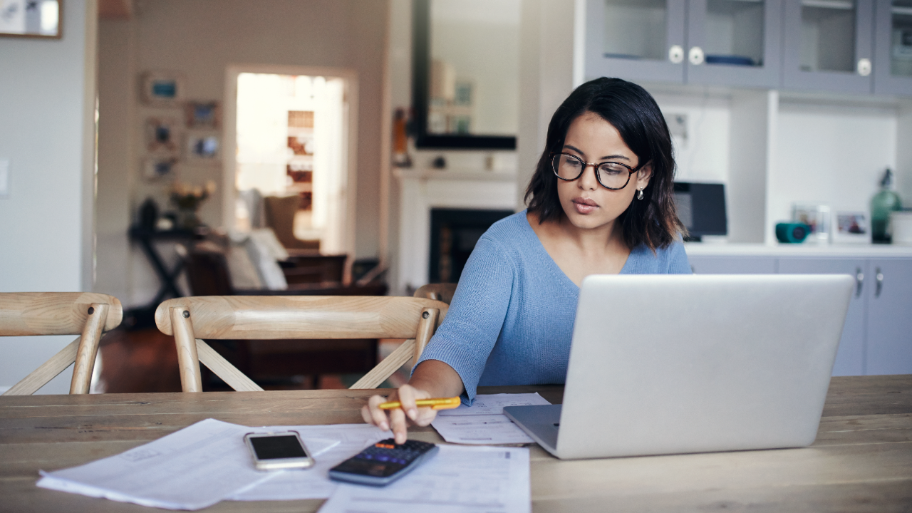 Woman calculating business budget with a laptop and calculator