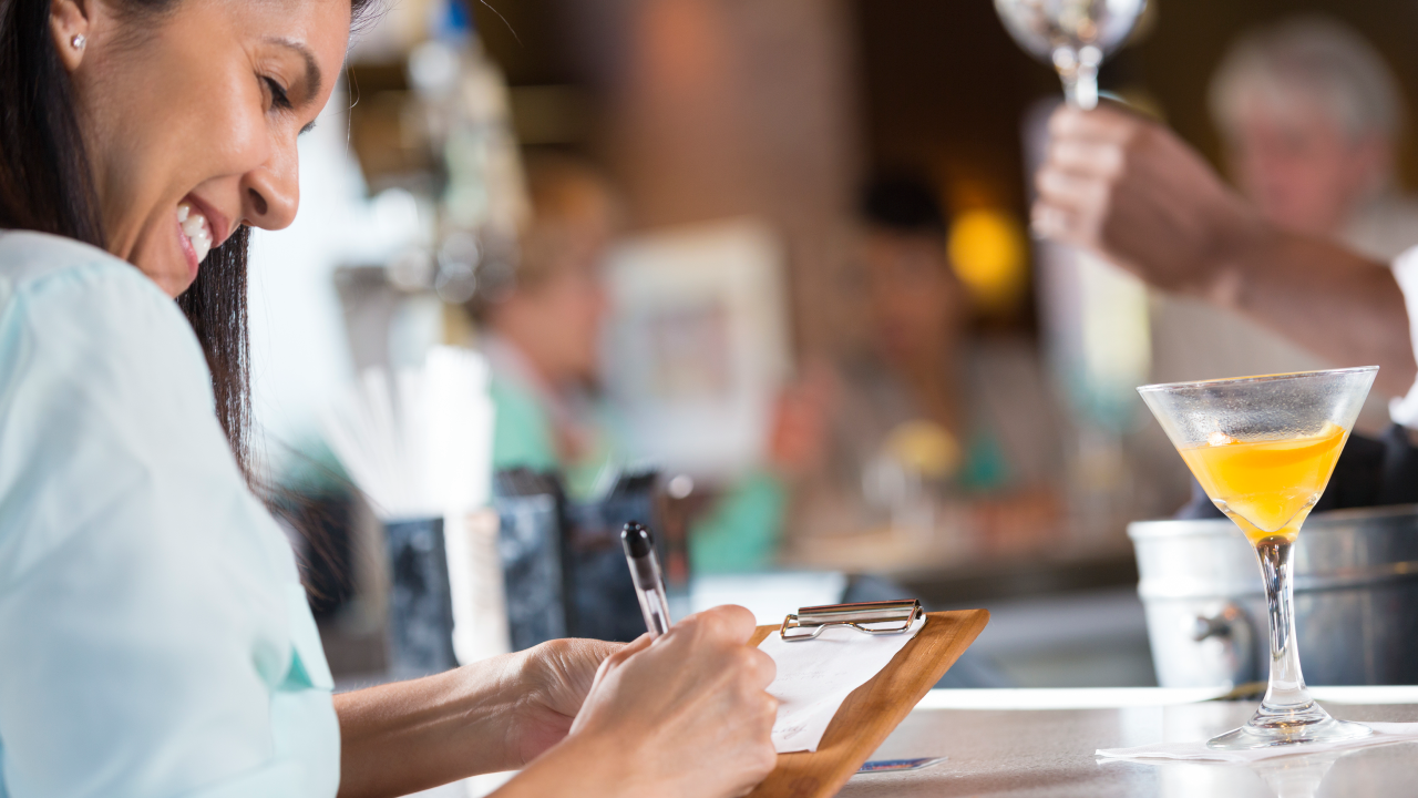 Woman signing receipt after paying bar tab in restaurant