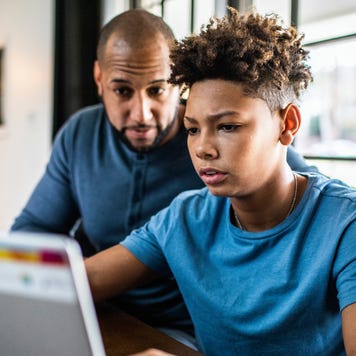 Father helping teenage son with financial planning in residential kitchen