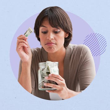 Woman putting money into a glass savings jar