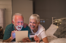Happy senior couple using credit card and digital tablet