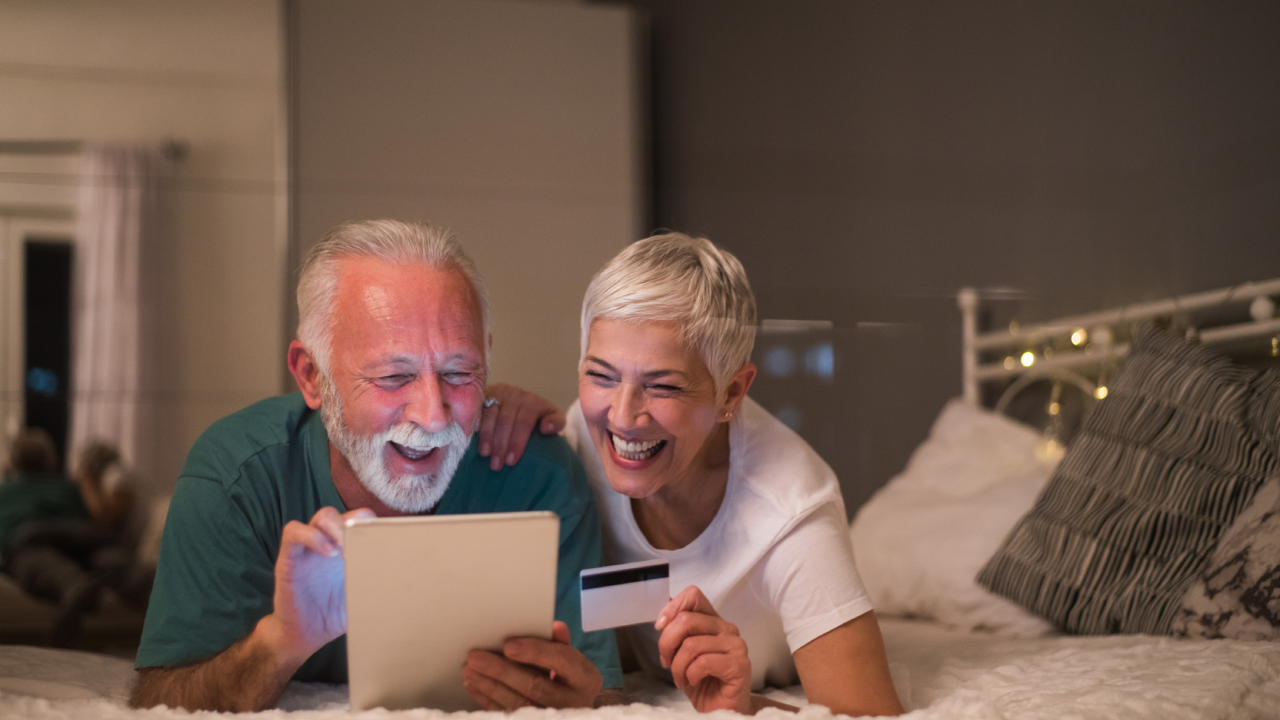 Happy senior couple using credit card and digital tablet
