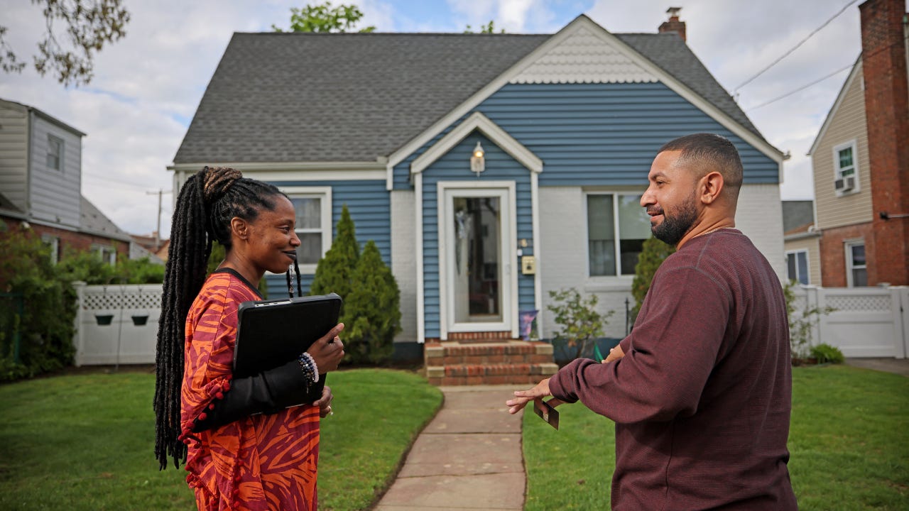 Real estate broker speaks with a potential buyer outside a house in Valley Stream, New York