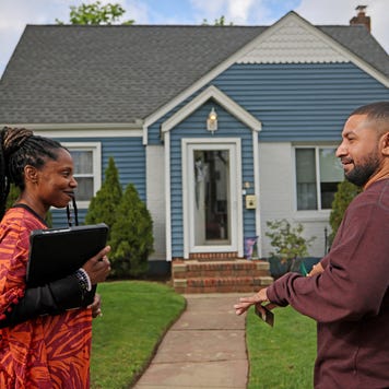 Real estate broker speaks with a potential buyer outside a house in Valley Stream, New York