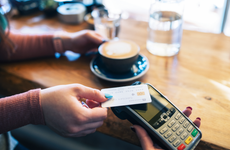 Clsoe-up of unrecognisable woman making contactless card payment in cafe.