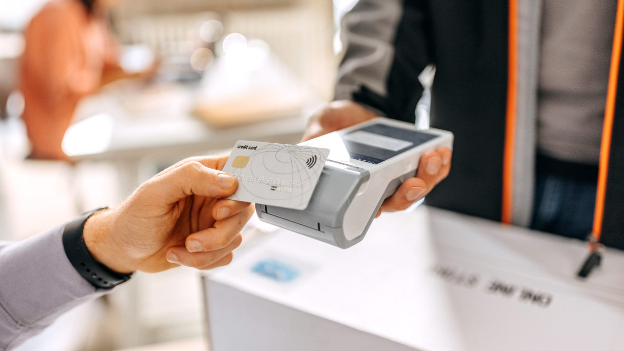 Close up of a man's hand paying delivery with credit card in a office, scanning on a card machine