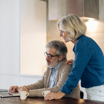 man with wife using laptop on kitchen table at home