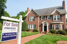 brick suburban home with for sale sign on front lawn