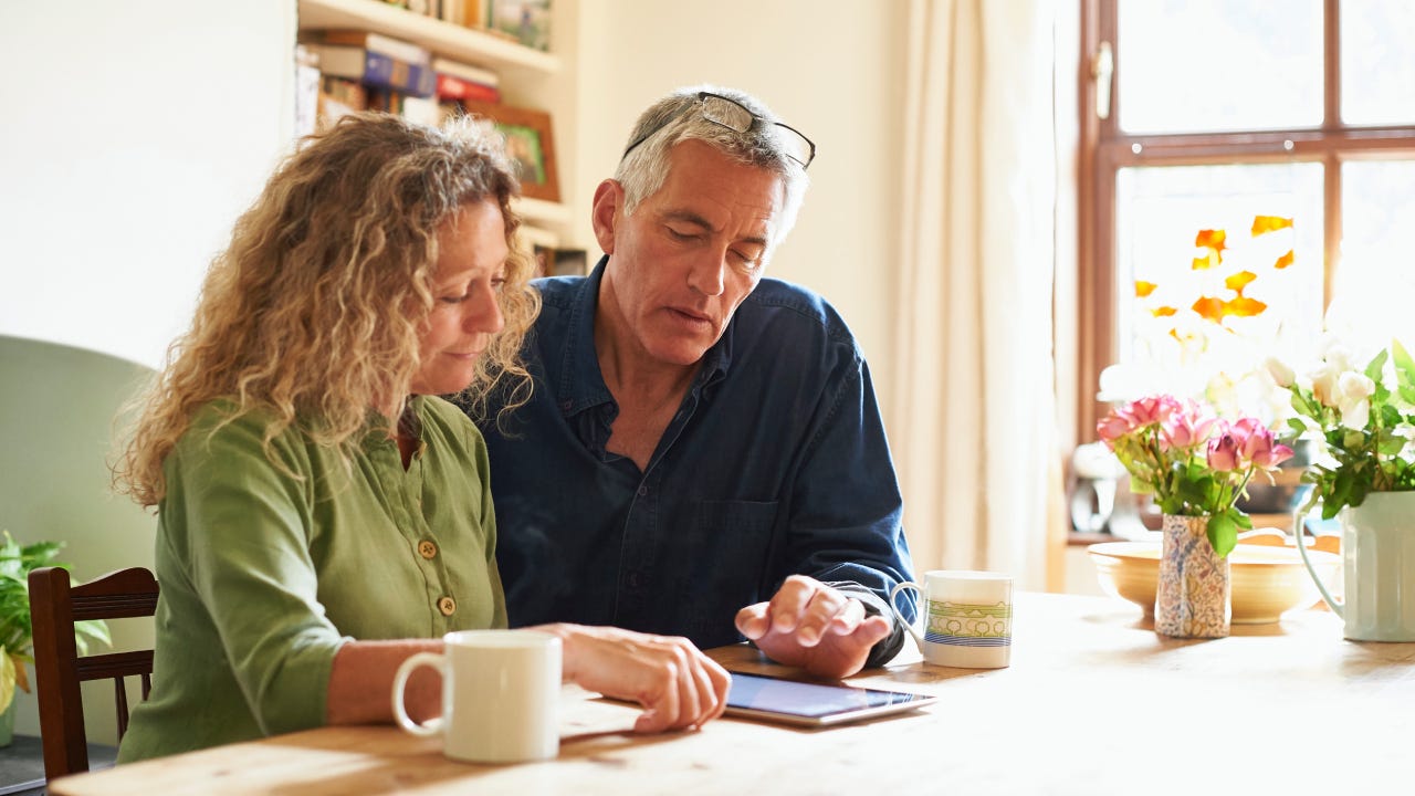 Couple sitting at table using digital tablet