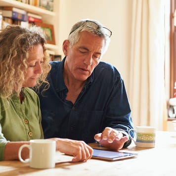 Couple sitting at table using digital tablet