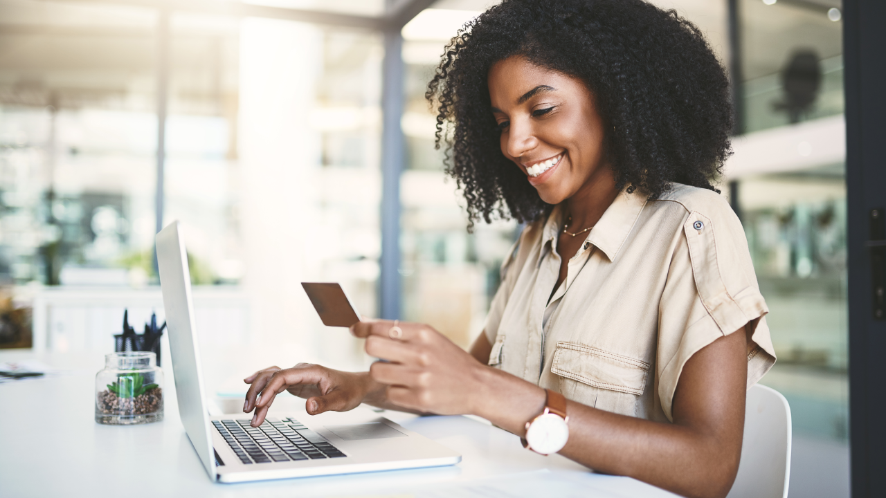 Shot of a young businesswoman using a credit card and laptop in a modern office