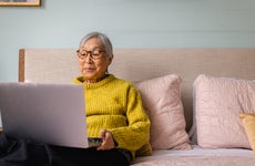 woman using laptop while sitting in bedroom