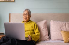woman using laptop while sitting in bedroom