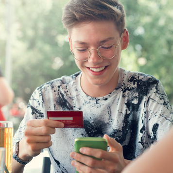 Teenager Boy and her friends Use credit card for shopping online in the cafeteria