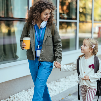 Girl with backpack holding her mother's hand and going to school.