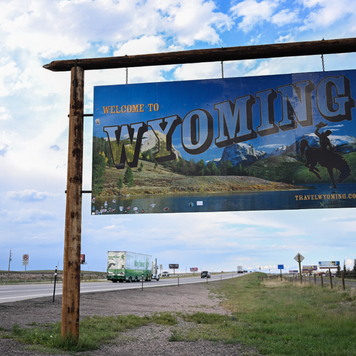 Cars and trucks drive past a Welcome to Wyoming sign south of Cheyenne, Wyoming