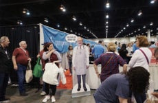 Attendees walk past a cardboard cutout of Warren Buffett