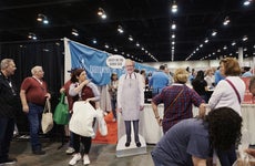 Attendees walk past a cardboard cutout of Warren Buffett