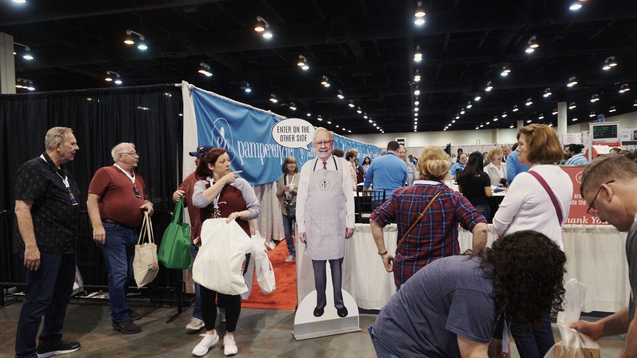 Attendees walk past a cardboard cutout of Warren Buffett