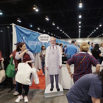 Attendees walk past a cardboard cutout of Warren Buffett