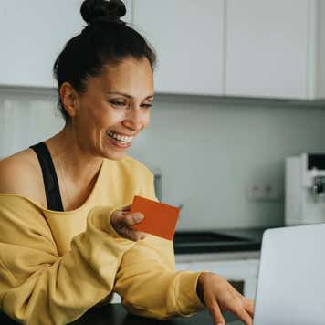 Smiling woman holding a credit card and typing on a laptop