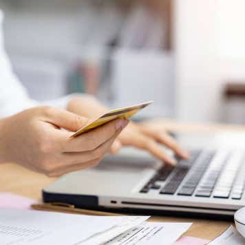 Woman using laptop and holding credit card, close-up