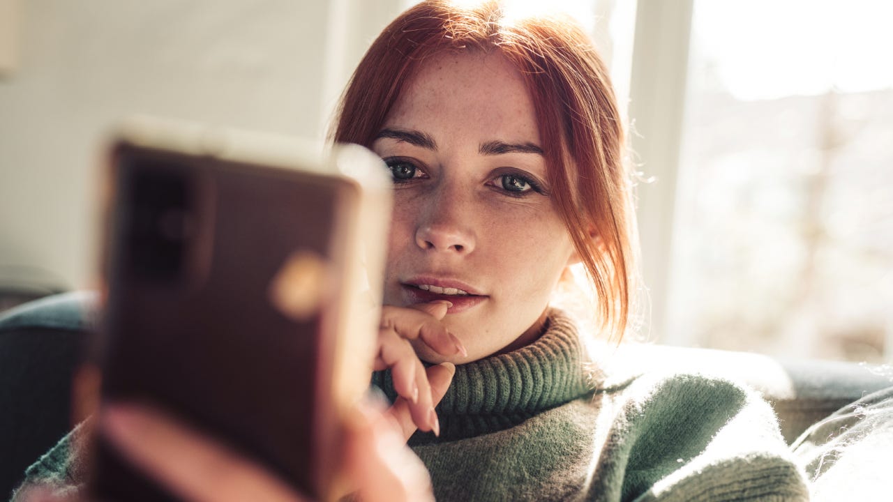 Woman with red hair looking on screen of her mobile phone