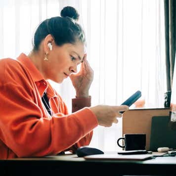 A distressed woman looks down at her phone.