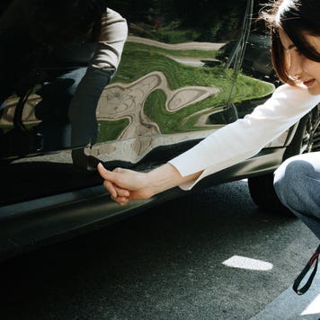woman inspecting damage on car
