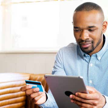 Black man holding credit card and tablet