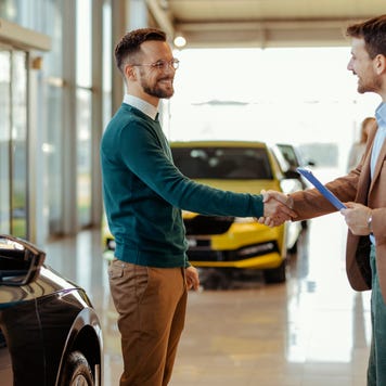 Two people shaking hands at a dealership