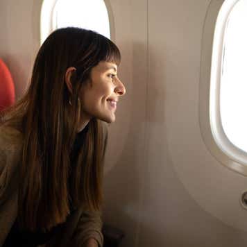 Smiling woman looks out airplane window.