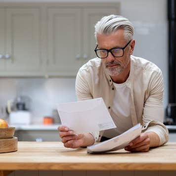 Man at home reading a letter he got in his mail at the kitchen – lifestyle concepts