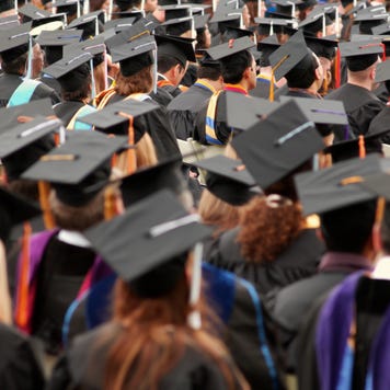 College graduates facing away from the camera standing for graduation