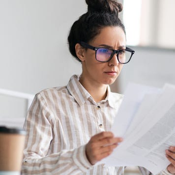 Woman with glasses reviews papers.