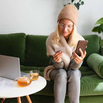 Woman paying bills while sitting on sofa