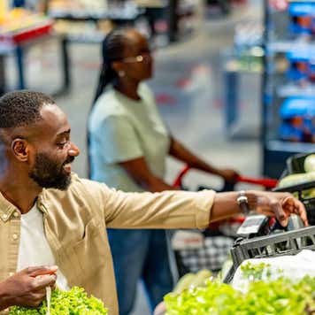 A man buying fresh vegetables while shopping at a supermarket.