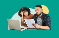 Couple looking concerned as they review financial documents while in front of an open laptop computer.