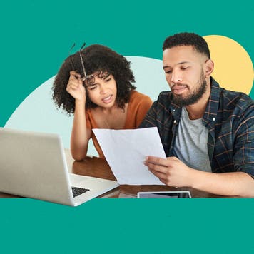 Couple looking concerned as they review financial documents while in front of an open laptop computer.