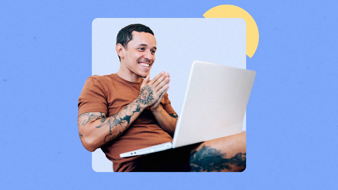 Young man with tattoos using a laptop and smiling